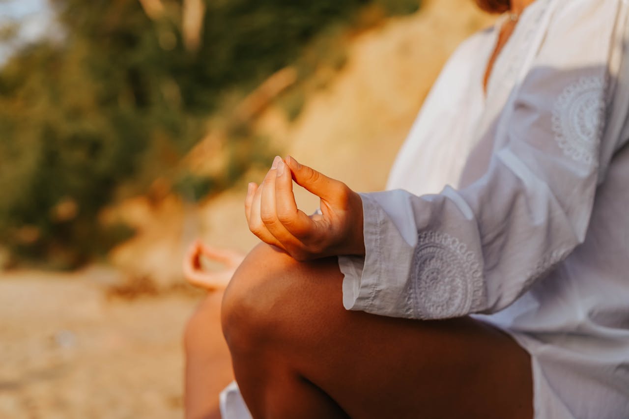 A close-up of a person meditating outdoors, capturing mindfulness at sunset on a beach.